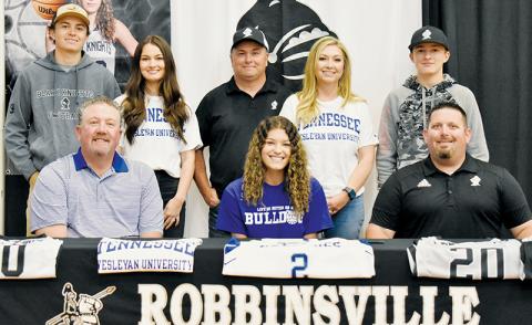 Lady Knights senior Yeika Jimenez (seated, center) signed to play college basketball at Tennessee Wesleyan on May 5. Sitting with Jimenez is Tennessee Wesleyan Lady Bulldogs head coach Jeff Rice (left) and Robbinsville Lady Knights head coach Lucas Ford. Standing in back (from left) are brother Carson Lovin, sister Cambrie Lovin, legal guardians Brandon and Haley Lovin, and brother Luke Lovin.