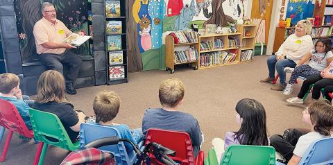 Donnie Orr (left) reads to children at Robbinsville Elementary School’s media center on Friday, as his sister Debbie Orr (right) waits his turn. The siblings were at the school to dedicate a reading nook in honor of their late mother Maxine Orr, who was a teaching assistant at the school for 30 years. Photo by Randy Foster/news@grahamstar.com