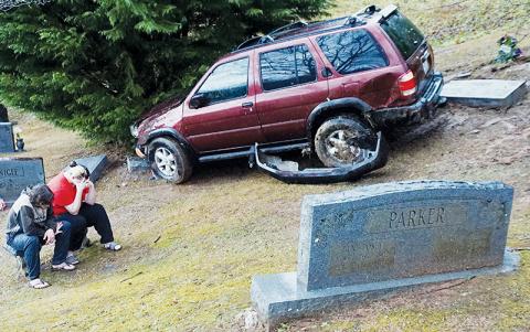 Phillip Graham of Almond and Destiny Williams of Robbinsville rest on a cemetery bench after their vehicle crashed at Lone Oak Cemetery on Dec. 7. Photo by Randy Foster/news@grahamstar.com