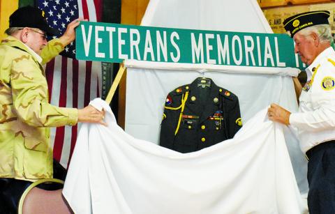 Vietnam War veteran Lamar Crisp (left) and American Legion Post 182 Commander Harold Phillips unveil the sign for Veterans Memorial Hill, which will share the same path as East Main Street in Robbinsville. Photos by Kevin Hensley/editor@grahamstar.com