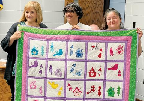 Graham County Schools Superintendent Angie Knight was brought to tears early at Tuesday’s board of education meeting, as she was presented with a quilt made by students at the county’s educational academy. Giving Knight the gift is Emmanuel Conde (center) and Cecelia Maney. Photo by Kevin Hensley/editor@grahamstar.com