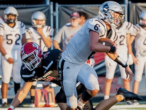 Robbinsville quarterback Bryce Adams breaks away from the pursuit of East Surry’s Luke Bruner during Friday’s 21-19 loss to the Cardinals. Photos courtesy of JR Willoughby Photography
