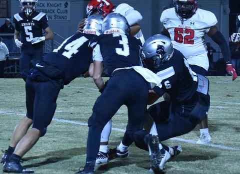 Robbinsville's Cameron Allison (14), Luke Lovin (3) and Bryce Adams (6) combine forces to drop Thomasville's Keshawn Carpenter during Friday's first-round playoff game. Photo by Bella Eddings/The Graham Star