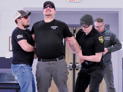 Reality sets in for Taylor Rennoldson as a Taser makes contact at Friday’s certification course. Holding Rennoldson are deputies  Logan Howarth (left) and Justin Stewart; chief detective Travis Brooks is in back, moments after deploying the Taser.