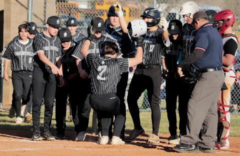 Freshman Easton Shuler (2) stomps onto home plate while being greeted by his  teammates after hitting a two-run homer Friday against Andrews. The long ball was part of a successful comeback bid for the Black Knights against the Wildcats. Photo by Kyla Garland/The Graham Star