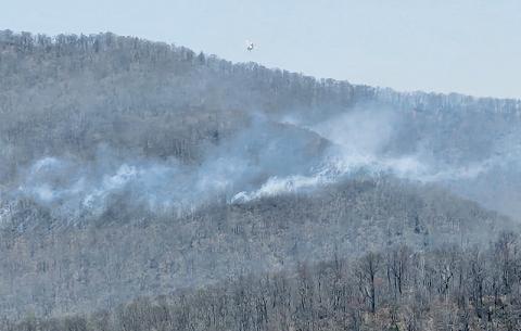 A helicopter flies over the Haoe Lead Fire, preparing to drop water from nearby Lake Santeetlah onto the widespread flames. Photo courtesy of Tory Lynnes/U.S. Forest Service