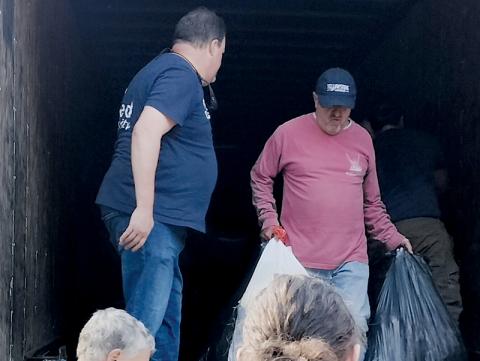 As part of the local effort to help those affected by Hurricane Helene last year, Tim Eller with  Robbinsville’s United  Community Bank (left, on truck) was one of many who responded to the call of delivering supplies to Buncombe County. Photo by Eric Reece/The Graham Star