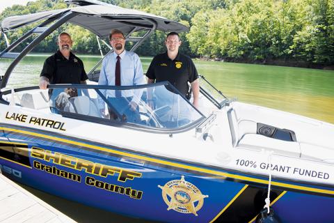 Graham County Sheriff Brad Hoxit, U.S. Rep. Chuck Edwards (R-Hendersonville) and Swain County Sheriff Brian Kirkland (from left) stand inside the $80,000 search and rescue boat that was obtained under the federal  Community Project Funding Grant on Aug. 15. The purchase of the boat and the recent acquisition of a $36,000 have both been questioned by the community. Photo by Kevin Hensley/editor@grahamstar.com