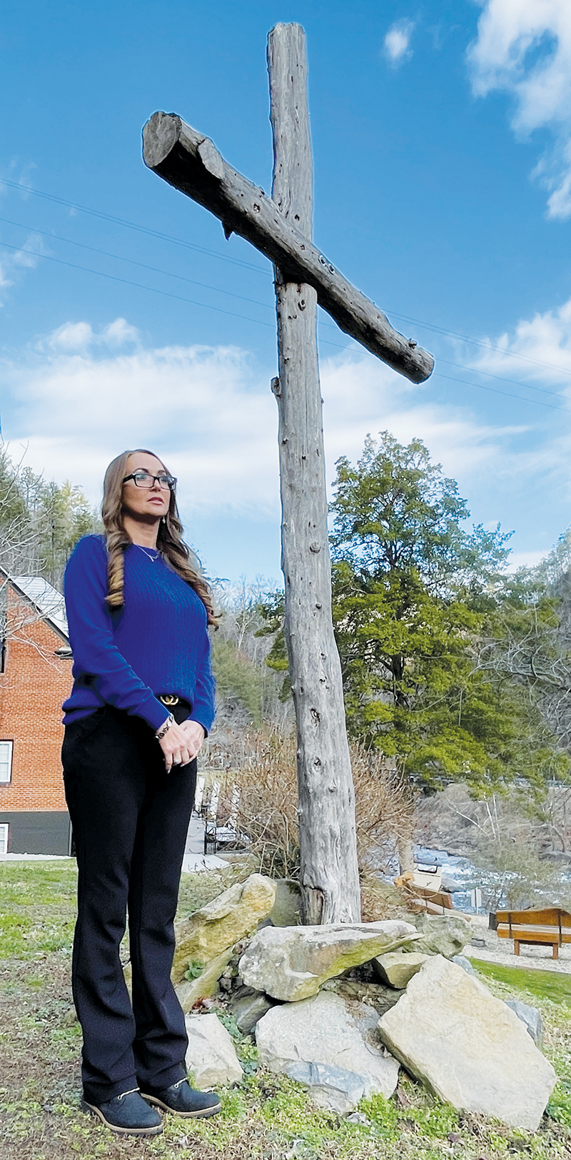 Valerie Frapp, events and marketing manager at Historic Tapoco Lodge, stands beside a timber cross overlooking the Cheoah River beside the lodge. Kimberly Vaught had the cross constructed to her specifications for Easter Sunday in 2019.