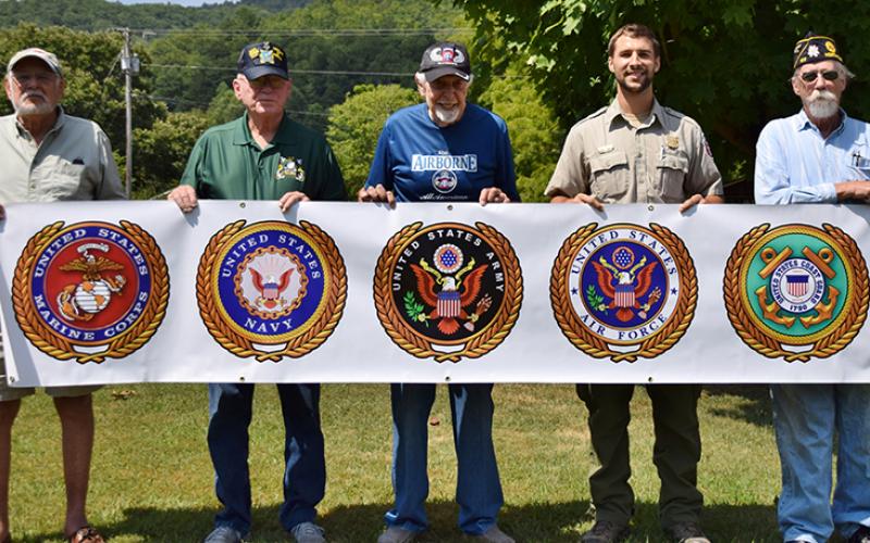 Bill Smith, Alan Garver, Mel Greene, Drew Ford and Hubert Merchant (from left) hold up the veterans banner that is now on-display at Stecoah. 