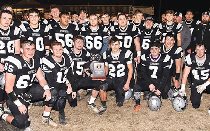 Members of the Robbinsville Black Knights crowd around the 1A Western Regional Championship trophy moments after defeating the Thomas Jefferson Classical Academy Gryphons 28-14 on Friday night. Photo by Byron Housley/The Graham Star