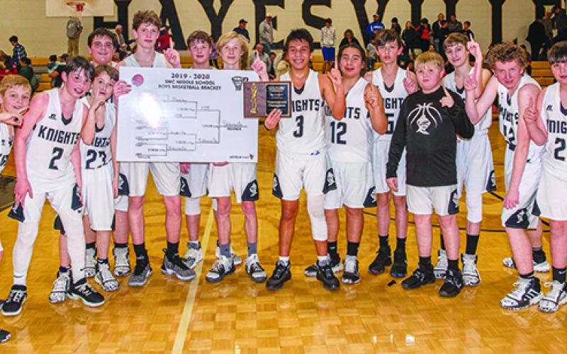 The Robbinsville Middle School Black Knights pose with the 2019-20 championship tournament bracket, moments after defeating the Hiwassee Dam/Ranger Eagles to win the title on Jan. 23 in Hayesville. From left are Dane Knott, Roman Jones, Luke Lovin, Tytan Teesateskie, Donovan Carpenter, Bryce Adams, Zeke Silvers, Xander Wachacha, Quinn Jumper, Andrew Scrivner, Drake Anderson, Austin Colangelo, Hugh Forbes and Isiac Collins. Photos by Byron Housley/The Graham Star