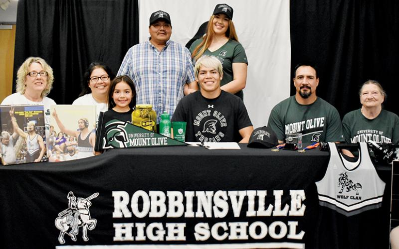 Ben Wachacha (seated, center) signed to wrestle for the University of Mount Olive on Friday. Seated with Wachacha are (from left) grandmother Debbie Bird, mother Monaka Wachacha, sister Amara Wachacha, father Randy Wachacha and grandmother Carolyn Wachacha. Standing in back are grandfather John Bird (left) and sister Aubrie Wachacha. Photo by Kevin Hensley/sports@grahamstar.com