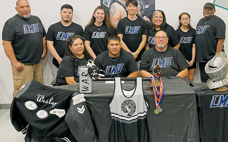 Carlos Wesley (seated, center) signed to wrestle at Lincoln Memorial University on Sunday. Surrounding Wesley are family and friends, including mother Scharlene Hardrick (seated, left) and Vincent Wesley, Bryan Wesley, Jasper Knighton, Staci Knighton, Seth Lawson, Jennifer Wesley, Briley Powers and Steven Hardrick (back row, from left). Photo courtesy of Todd Odom/Contributing Photographer