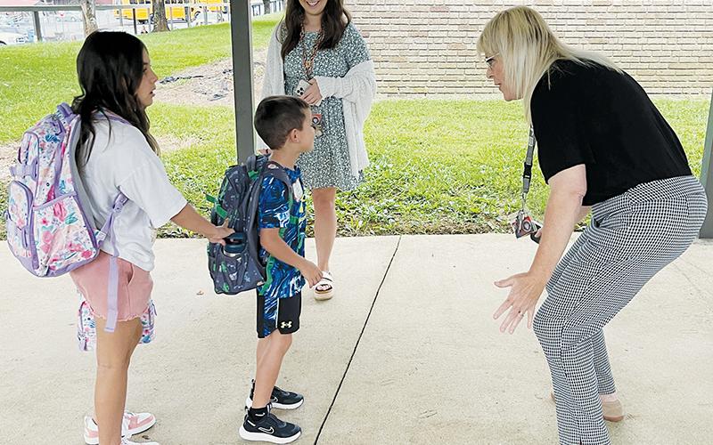 Robbinsville Elementary School faculty members Shayla Bush (background) and Lynn Lynn (right) were all smiles while greeting McKynlee Adams (left) and Maverick Ayers (center) at the beginning of the 2022-23 school year Monday. Photo by Randy Foster/news@grahamstar.com