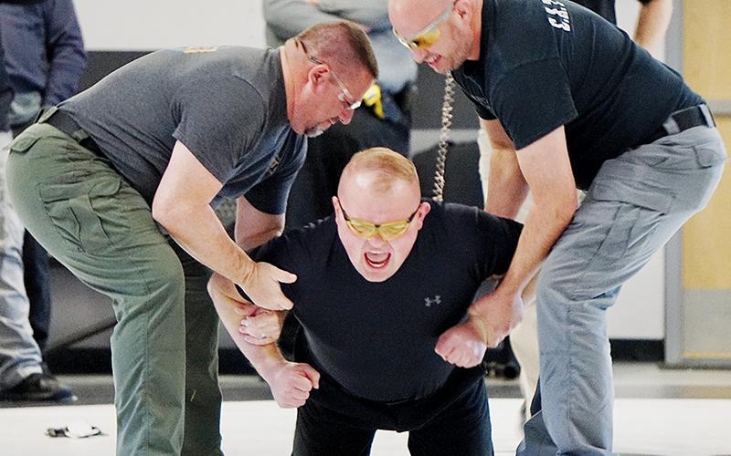 Patrol Deputy Chase Hughes (center) grimaces as he is tased by trainer Travis Brooks, a detective with the Graham County Sheriff’s Office. Hughes was braced by Capt. Joseph Jones (left) and Narcotics Officer Matt Cox. Photo by Randy Foster/news@grahamstar.com