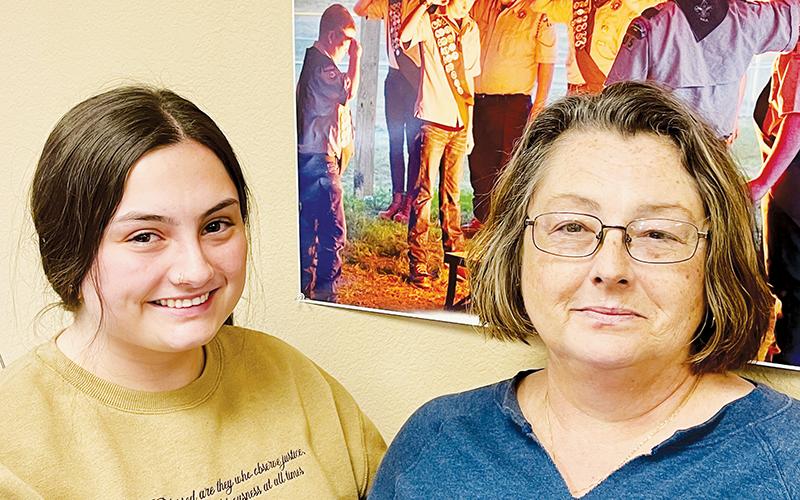 Willow (left) and Lisa Trantham gather underneath a photo The Graham Star proudly has on display. Gentry Trantham – brother to Willow, son of Lisa and Scott – is on the far left of the photo. Gentry passed away Nov. 3. Photo by Randy Foster/news@grahamstar.com