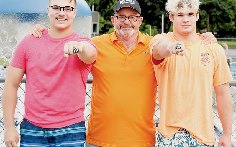 Robbinsville Wrestling held a pool party for the team June 15. Head coach David Haney (center) surprised his three state champions with their commemorative rings at the end of the gathering. Koleson Dooley is at left; Kage Williams at right. Not pictured is Alexis Panama. Photo by Kevin Hensley/sports@grahamstar.com