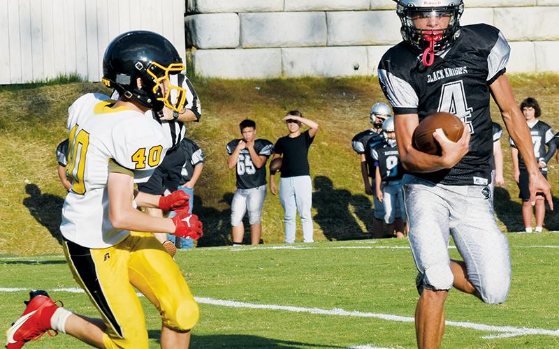 Under the pursuit of Murphy’s Brodie Betts, JV Black Knight Cameron Allison eyes a cut upfield during Sept. 7’s home tilt with the Bulldogs. Photo by Danielle Crabtree/The Graham Star