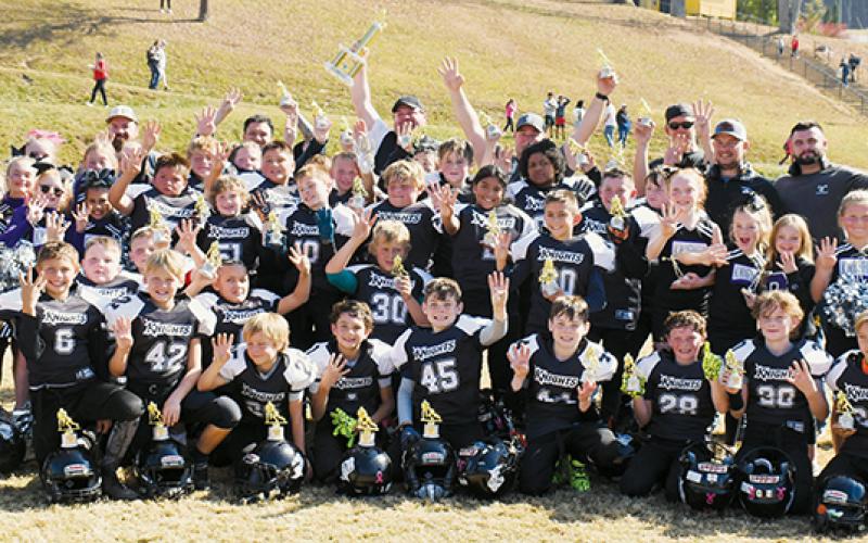 The Robbinsville Mites make it official Saturday, gathering around the 2023 Cracker Bowl Championship trophy to soak up the moment after winning their fourth title in a row. Photo by Kevin Hensley/sports@grahamstar.com