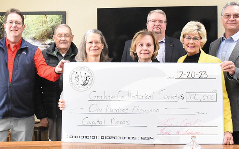 The loop concluded with a visit to the Phillips and Jordan office in Robbinsville, where a check for $100K was afforded to the Graham County Historical Association for capital needs. From left are Corbin, association treasurer Terri Phillips, association secretary Carolyn Stewart, association president Edd Satterfield, association board member Connie Orr and Gillespie. Photo by Ruby Annas/news@grahamstar.com