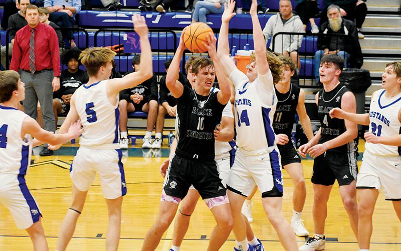 Forward Bryce Adams fights through the interior defense of Smoky Mountain’s Cameron Fowler (5) and Ace Pregner (14) on Dec. 27. Although the junior’s efforts in the game resulted in a double-double, the Black Knights suffered their first loss of the year. Photos by Fala Welch/The Graham Star