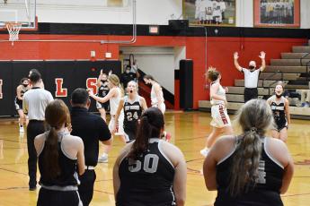 Robbinsville's Kensley Phillips (24) and Gabby Hooper (3) kick off the victory celebration as the official signals the end of the Lady Knights' 72-60 comeback win at East Surry on Thursday night. Photo by Kevin Hensley/editor@grahamstar.com