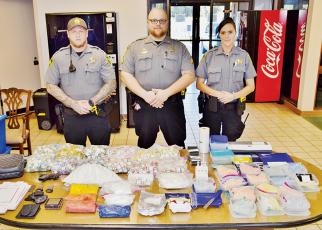 Patrol Officer Jessy Miller, Patrol Sgt. Graham Page and Patrol Officer Alexandria Parris stand with items seized after a Sept. 23 license check, which led to the arrest of Acworth, Ga. resident Michael Thomas Garcia. Photo by Art Miller/amiller@grahamstar.com