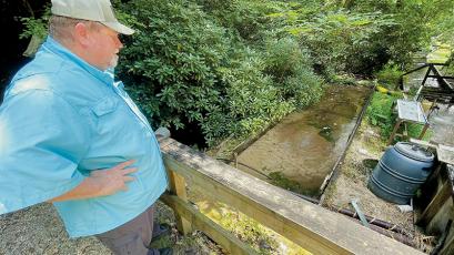 Duane Wilkey looks at the silt-filled raceway at his trout farm on Hunting Boy Branch on Aug. 25. Photo by Randy Foster/news@grahamstar.com