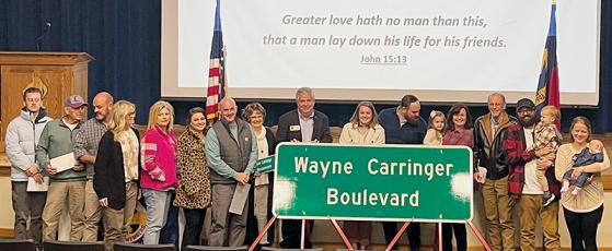 Family members pose with the new street sign for Wayne Carringer Boulevard, during a dedication ceremony at Robbinsville High School on Friday. Photo by Randy Foster/news@grahamstar.com