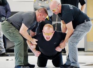 Patrol Deputy Chase Hughes (center) grimaces as he is tased by trainer Travis Brooks, a detective with the Graham County Sheriff’s Office. Hughes was braced by Capt. Joseph Jones (left) and Narcotics Officer Matt Cox. Photo by Randy Foster/news@grahamstar.com