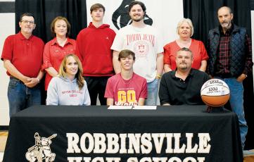 Surrounded by family, Robbinsville senior Brock Adams signed to play basketball at Bryan College on Monday. Sitting with Brock are his mother Andrea and father Tommy. Standing in back (from left) are grandparents Roger and Lisa Orr; brothers, Bryce and Reece Adams; and grandparents Louise and Boyd Adams. Photo by Kevin Hensley/sports@grahamstar.com
