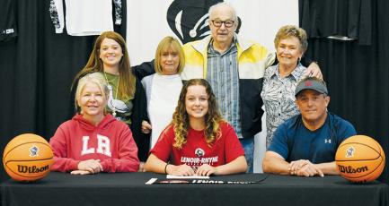 Desta Trammell signed to play basketball at Lenoir-Rhyne University on May 3. Seated with her are mother Kimm (left) and father Ritchie. Standing in back (from left) are cousin Shayla Bush,  grandmother Beverly Camden, grandfather Wesley Trammell and grandmother Lib Trammell. Photo by Kevin Hensley/sports@grahamstar.com
