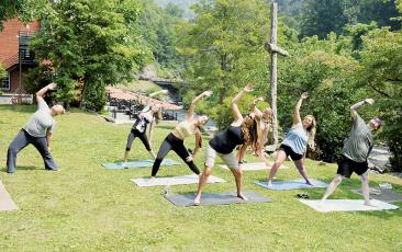 Tapoco Lodge Mountain Spa’s Tiffany Duke (left) leads a yoga class through the “Peaceful Warrior” pose June 17. With her coming aboard several months ago, Duke has expanded her reach in the county to two different resorts. Photos by Kevin Hensley/editor@grahamstar.com